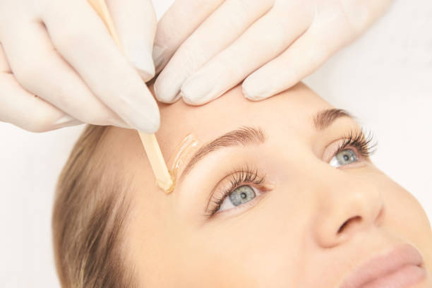 Woman receiving eyebrow treatment with applicator stick