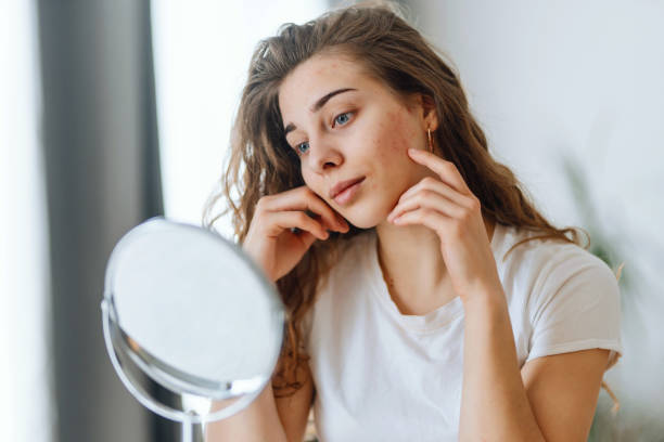 Young woman examining her face in a mirror