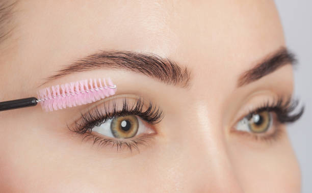 Applying eyebrow gel on woman's eyebrows with brush tool