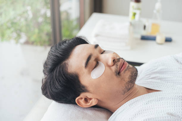 Man relaxing with eye patches in spa setting