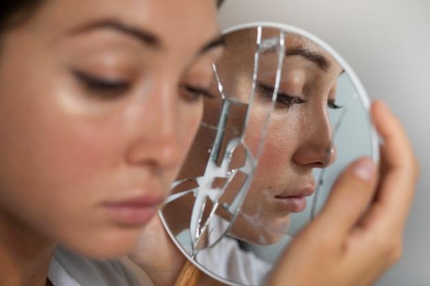 Woman examining her face with a magnifying mirror